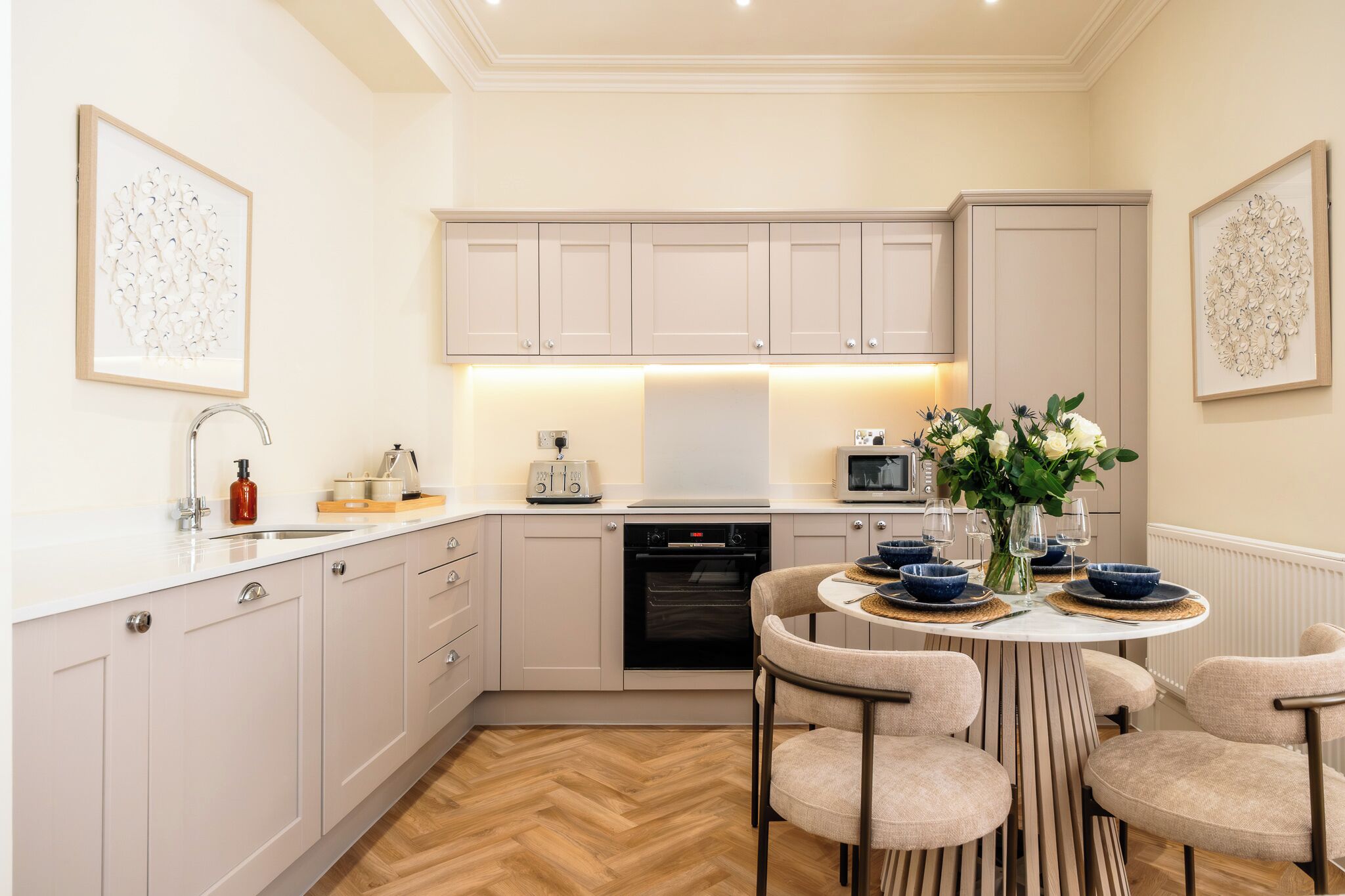 Una cucina moderna con mobili bianchi, un tavolo da pranzo con sedie e un'isola centrale con un vaso di fiori.