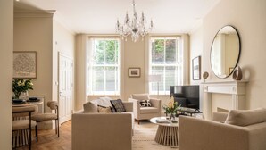 A living room with a fireplace, a chandelier, and a television. - Stunning Flat in Centre of Cheltenham (Cheltenham)