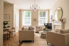 A living room with a fireplace, a chandelier, and a television. - Stunning Flat in Centre of Cheltenham (Cheltenham)