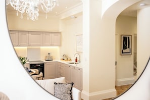 A modern kitchen with light-colored cabinets, a chandelier, and a dining area with a table and chairs. - Stunning Flat in Centre of Cheltenham (Cheltenham)