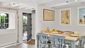 A dining area with a table set for four, chairs, a bowl of fruit, and a teapot. - Bobs Cottage, Porlock Weir (Porlock Weir)