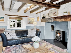 A cozy living room with a fireplace, a leather sofa, and a patterned rug.