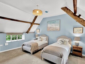 Quarto com duas camas, janela com vista, ventilador de teto e obras de arte nas paredes.