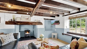 A cozy living room with a fireplace, leather sofas, a patterned rug, and a television. - Bobs Cottage, Porlock Weir (Porlock Weir)