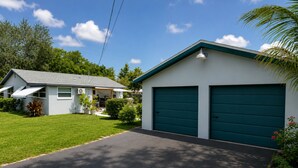 A residential property with a garage, a lawn, and a house with a grey roof. - Beautiful remodeled House in Nice area 5 min from downtown. (Fort Myers)