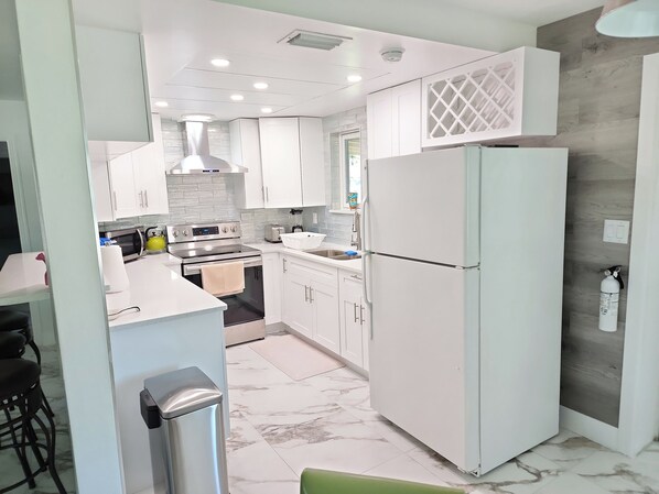 A modern kitchen with white cabinets, a stainless steel stove, and a refrigerator.