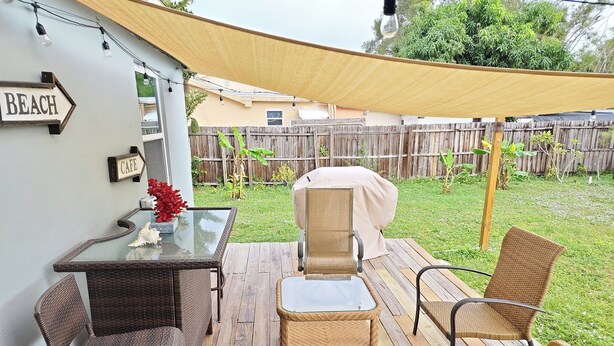 An outdoor patio with wicker furniture, a glass table, and a covered grill area. - Beautiful remodeled House in Nice area 5 min from downtown. (Fort Myers)