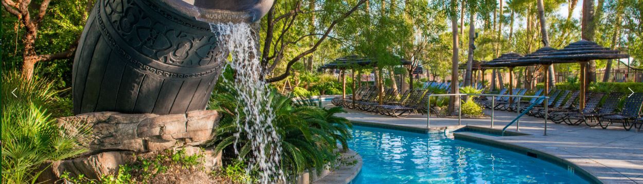 Un espace piscine agrémenté d’une cascade, de chaises longues et d’une pergola.