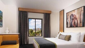 A hotel room with a bed, a desk, a window with curtains, and a painting on the wall. -  1 bedroom Luxury Resort Bora Bora (Las Vegas)