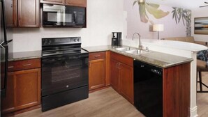 A kitchen with wooden cabinets, a stainless steel microwave, a black oven, a dishwasher, and a sink. -  1 bedroom Luxury Resort Bora Bora (Las Vegas)