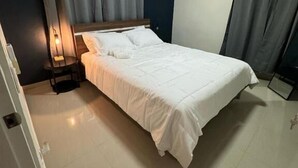Ein Schlafzimmer mit Bett, Vorhängen, einem Nachttisch und einer Wand-Klimaanlage.