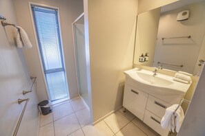 A bathroom with a sink, mirror, towel rack, and a window with blinds.