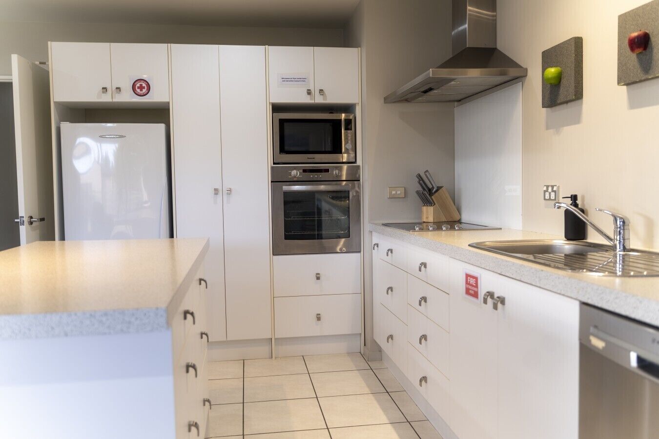 A modern kitchen with white cabinets, stainless steel appliances, a built-in oven, microwave, and a stainless steel sink.