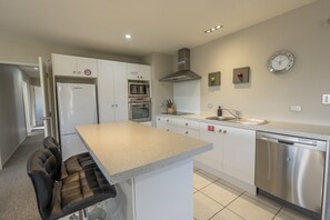 A modern kitchen with a central island, stainless steel appliances, and a clock on the wall.