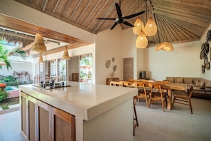 Uma sala ampla com uma grande mesa de jantar de madeira, um sofá e um ventilador de teto.