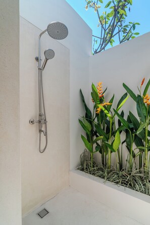 Eine moderne Dusche mit gebogener Form, einer an der Wand montierten Armatur und einem kleinen Fenster.