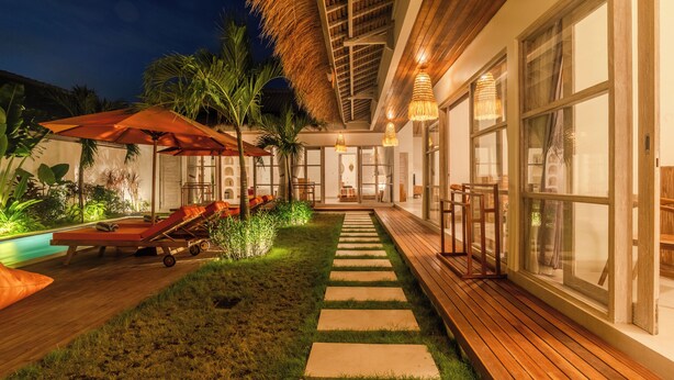 A well-lit outdoor area with a pool, lounge chairs, and a pathway leading to a building. - 4BR Villa Vaimala Tropical Home in Seminyak (Badung)