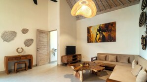 A living room with a wooden coffee table, sofa, and TV stand. - 4BR Villa Vaimala Tropical Home in Seminyak (Badung)