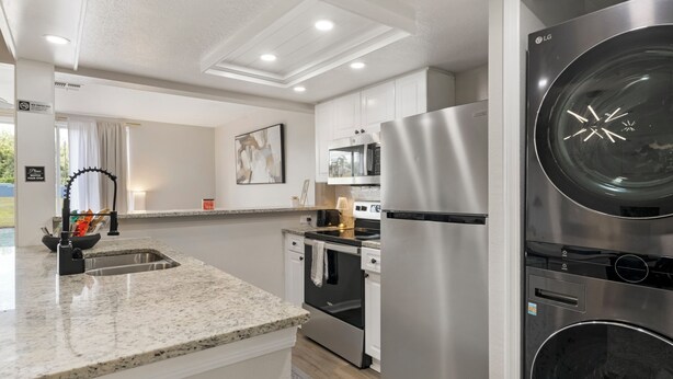 A modern kitchen with stainless steel appliances, a granite countertop, and a pendant light. - Spacious 3-bedroom apartment near Disney (Davenport)