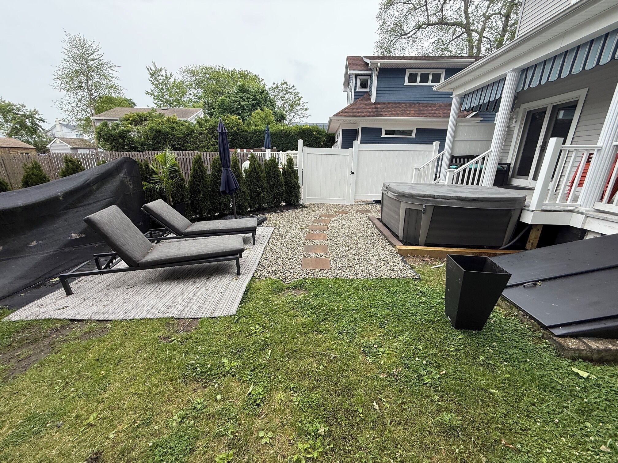 Un jardin avec un jacuzzi, des chaises longues et un petit espace patio.