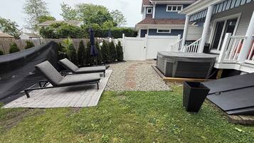 Un jardin avec un jacuzzi, des chaises longues et un petit espace patio.