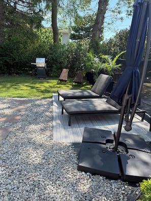 Eine Terrasse mit zwei Loungesesseln, einem Grill und einem Wasserspiel.