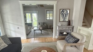 A living room with a sofa, armchair, coffee table, and a painting on the wall. - Beach Retreat w/ Hot Tub, Wraparound Porch, beach passes, bikes - Sleeps 12 (Bradley Beach)