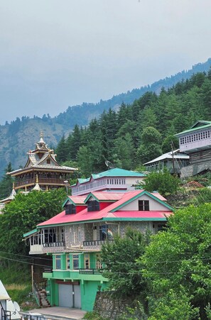 A traditional building with a multi-tiered roof, surrounded by lush greenery and hills in the background.