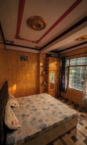A wooden room with a bed, a window with curtains, and a ceiling with decorative elements.