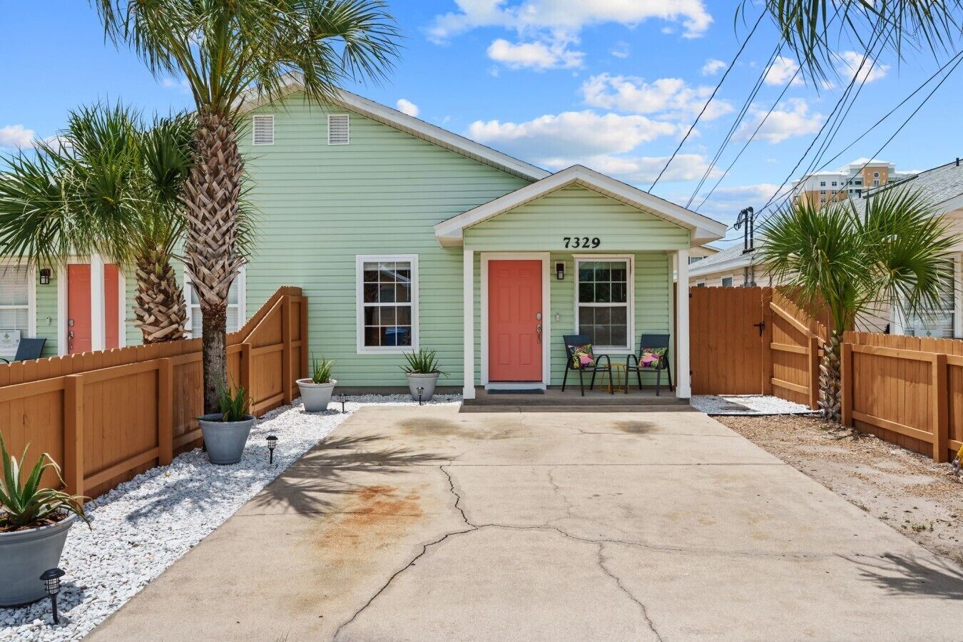 A single-story house with a green exterior, a red door, and the number 7329 on the front.