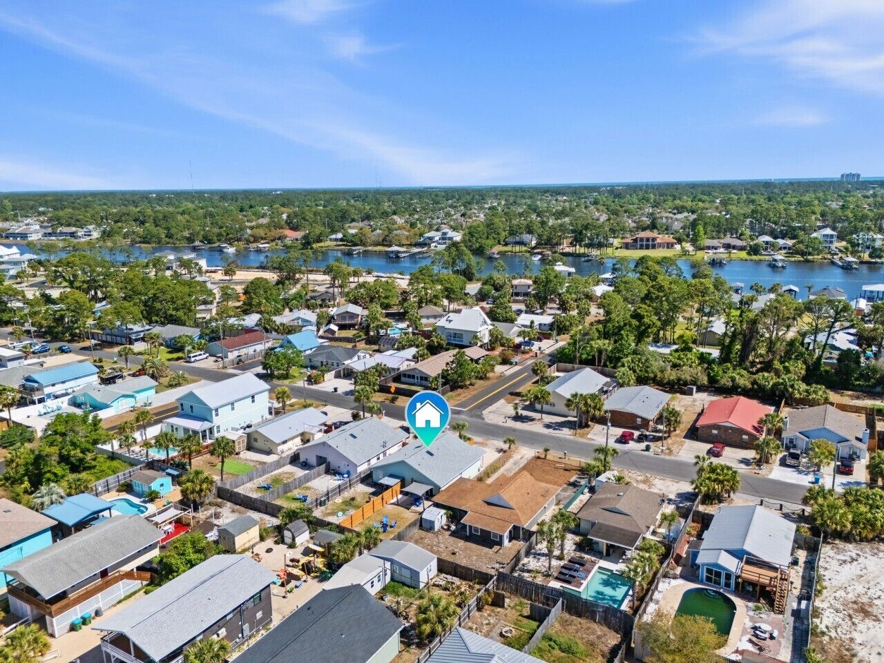 An aerial view of a residential area with houses, a body of water, and a clear sky.