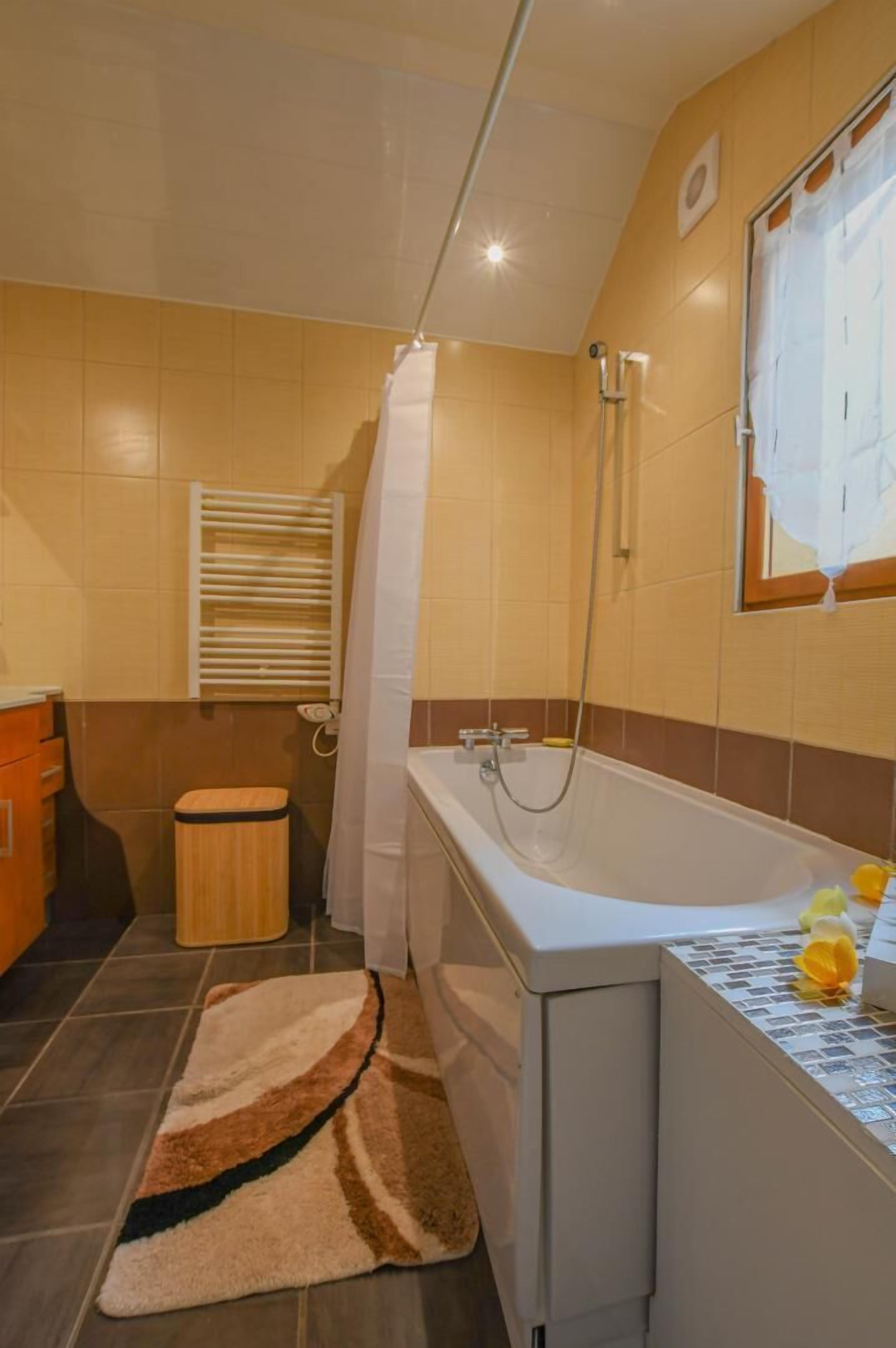 Un baño con bañera, ducha y ventana con persianas.