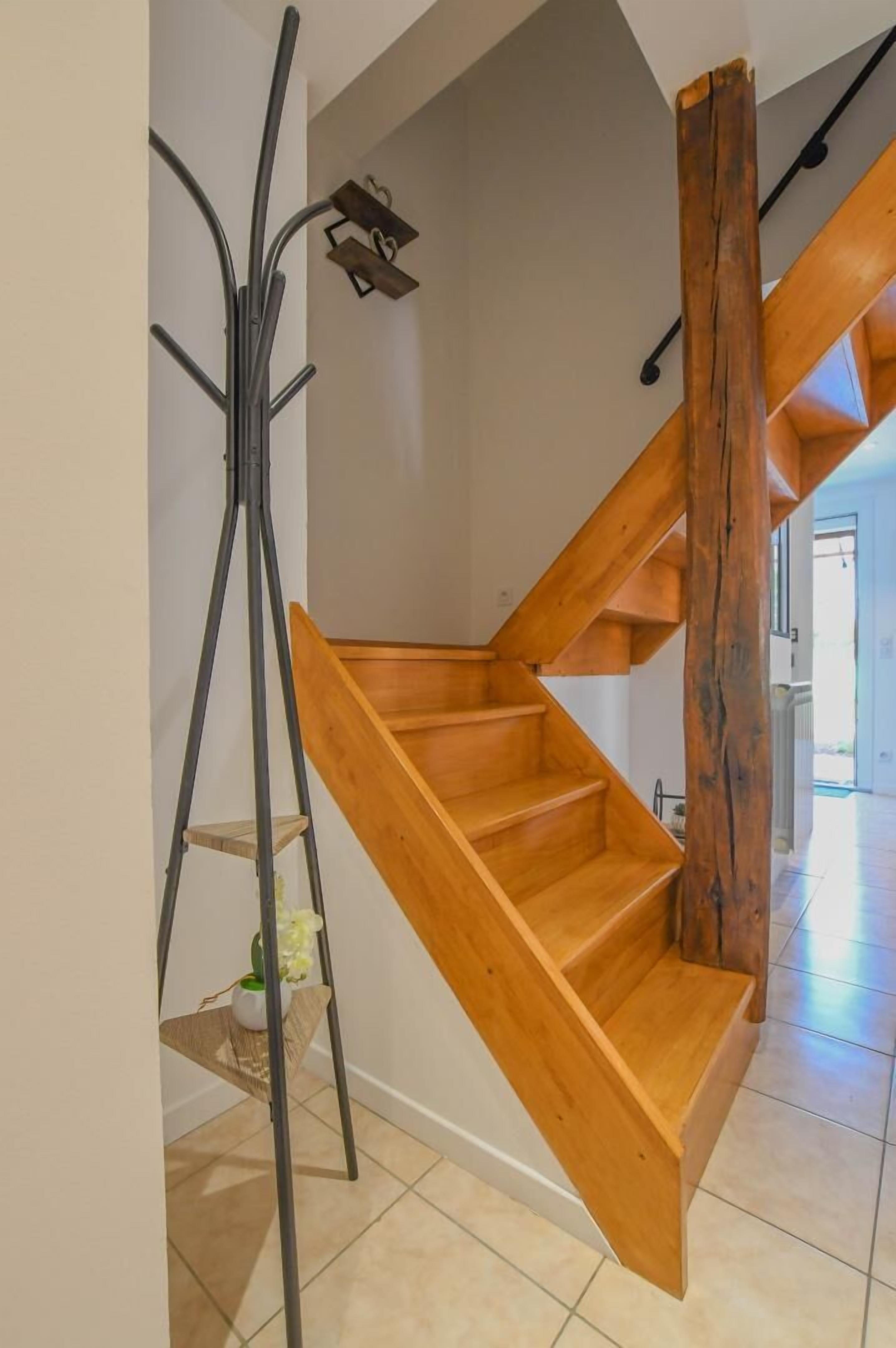 Una escalera de madera con barandilla de metal y una plataforma de madera al final.