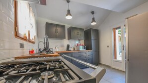 Une cuisine moderne avec une cuisinière à gaz, des meubles de couleur sombre et des luminaires suspendus.