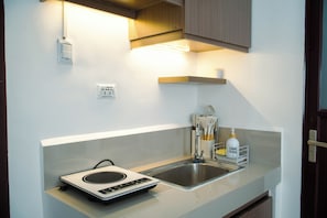 A compact kitchen with a built-in scale, a sink, and a countertop with a bottle of Dist. Orange. -  PRIME LOCATION • NEW 1BR CONDO FOR RENT (Lapu-Lapu)
