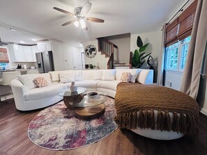 A living room with a sectional sofa, a coffee table, a round rug, a ceiling fan, and a window with curtains. -  Spacious 5-bedroom, 2 kitchens, 2 master bedrooms with a finished basement. (Austell)