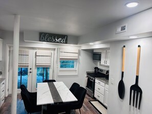 A modern kitchen with a dining table, white cabinets, a microwave, and a stove. -  Spacious 5-bedroom, 2 kitchens, 2 master bedrooms with a finished basement. (Austell)