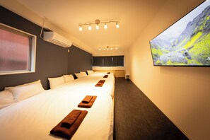 A hotel room with a large bed, a flat-screen TV, and a window with blinds. - KANDA URBAN SUITES (Chiyodaku Uchikanda)