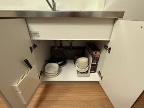 A kitchen with a stainless steel sink, a dish rack, and a box of disposable plates. - KANDA URBAN SUITES (Chiyodaku Uchikanda)