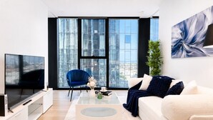 Een moderne woonkamer met een grote televisie, een bank, een salontafel en een fauteuil.