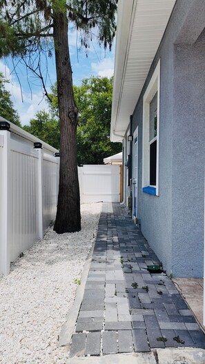 A pathway leading to a building with a white fence and a tree. - Cozy modern studio (Tampa)