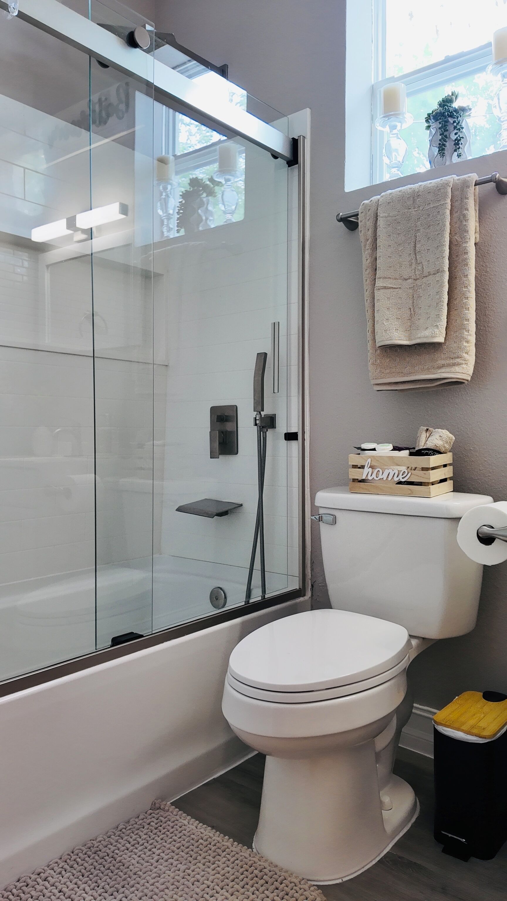 Un bagno moderno con cabina doccia in vetro, un water e un piccolo scatolino di legno con la scritta 'home' appeso al muro.