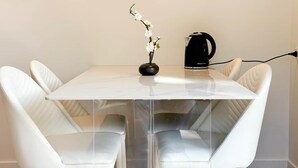 A modern dining area with a white table, clear glass panels, and white leather chairs. - Queenstown Garden - Lake View (Queenstown)