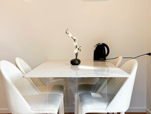 A modern dining area with a white table, clear glass panels, and white leather chairs. - Queenstown Garden - Lake View (Queenstown)