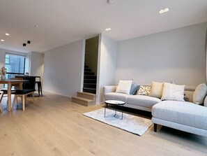 Ein modernes Wohnzimmer mit Sofa, Couchtisch und Essbereich.