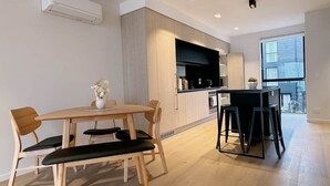 Una cocina moderna con armarios de madera, un comedor con una mesa y sillas de madera, y un amplio ventanal que proporciona luz natural.