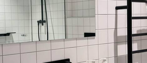 A bathroom with a white sink, black towel rack, and a mirror above the sink.