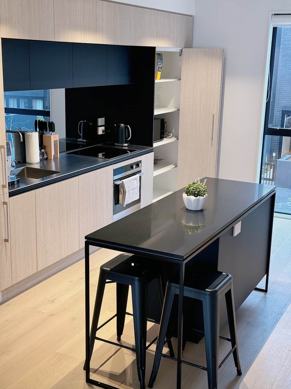 Eine moderne Küche mit schwarzem Arbeitsplatz, Edelstahlgeräten und Holzschränken.