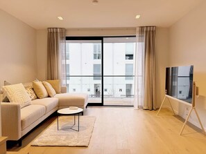 A modern living room with a sofa, coffee table, and TV on a stand. - Central City Garden - Free Parking (Christchurch)