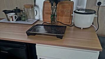 Une cuisine équipée d’un lave-vaisselle, d’une mijoteuse, d’une bouilloire et d’une machine à café.